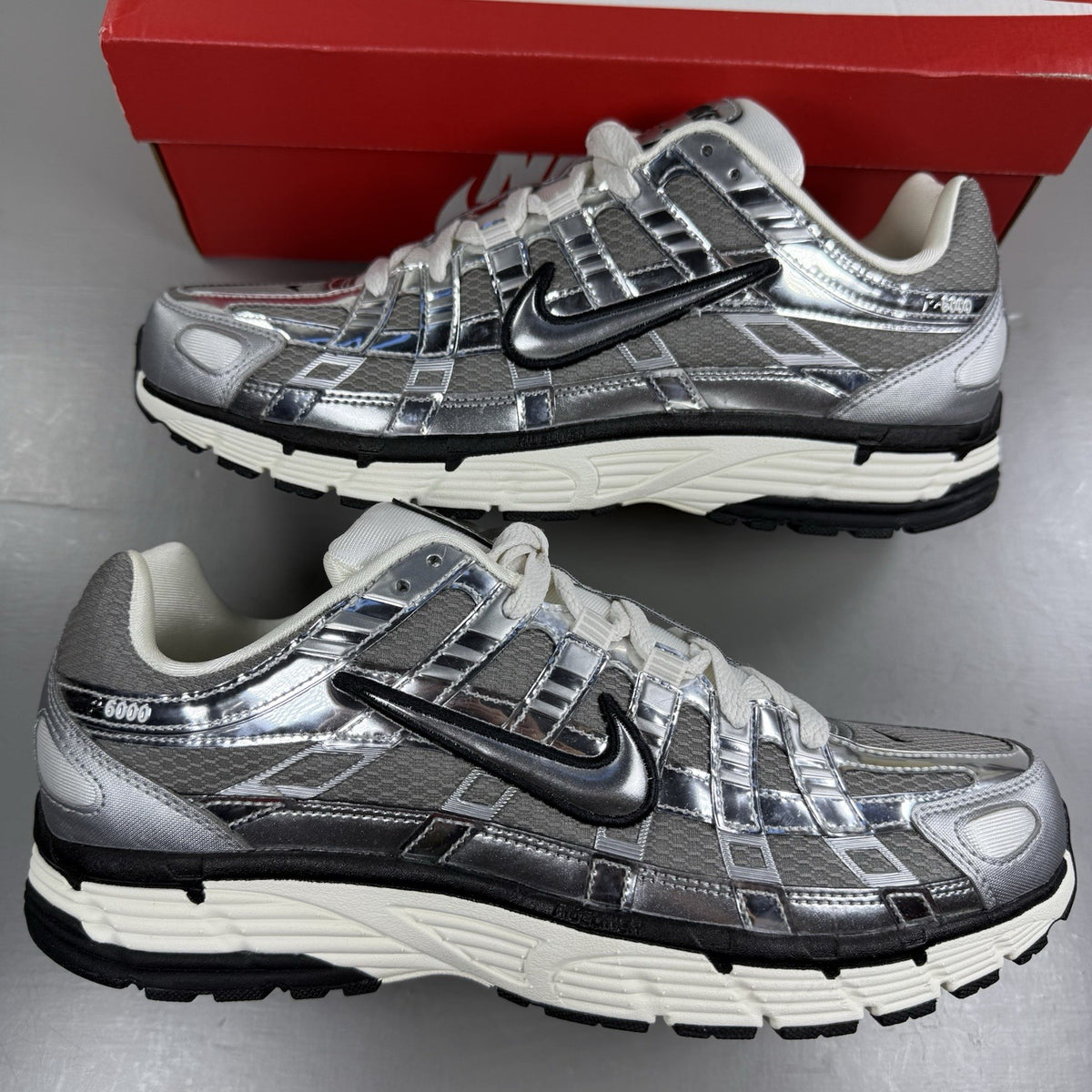 Nike P-6000 metallic silver trainers with black accents and white detailing.