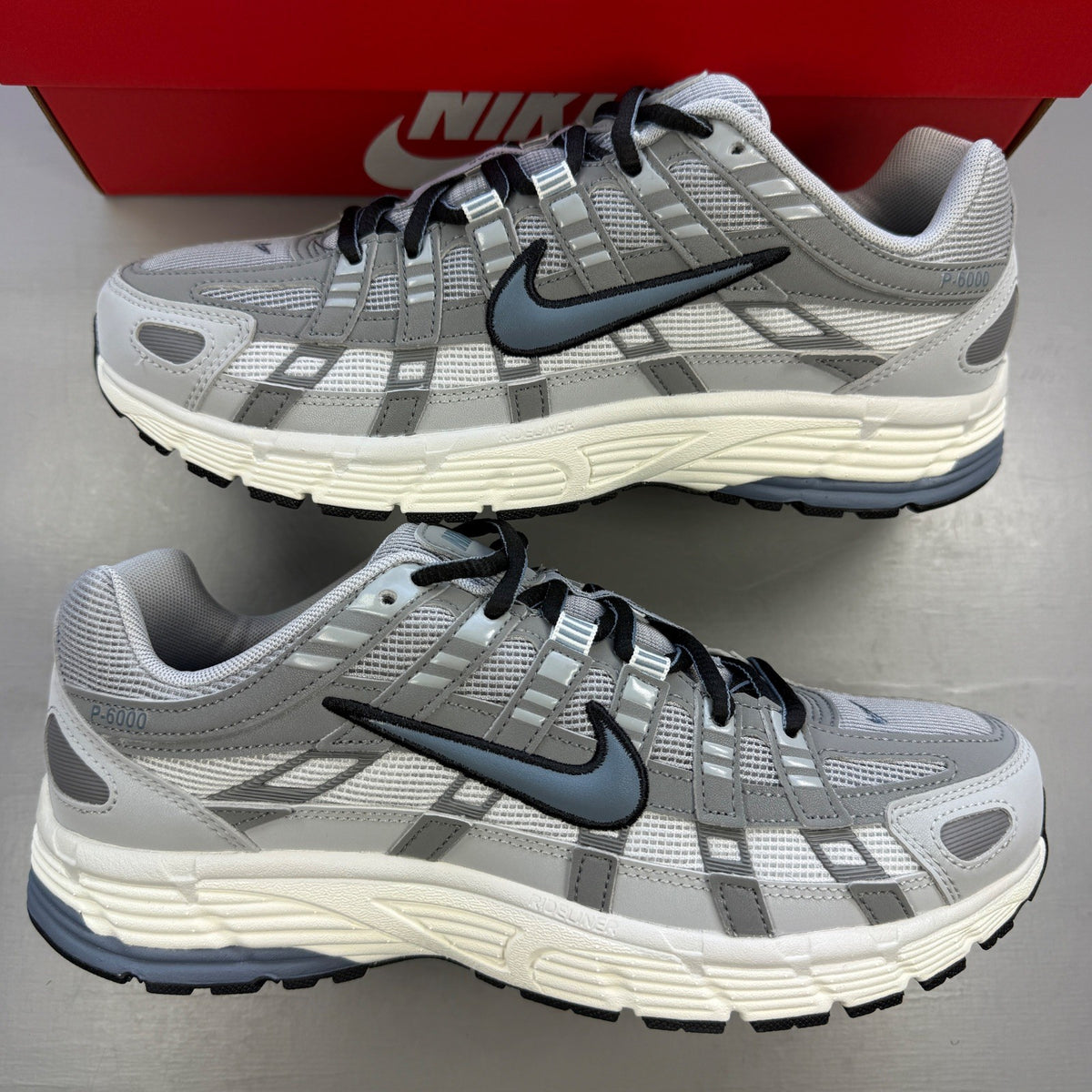 Nike athletic shoes light smoke grey with blue graphite accents and logo details.