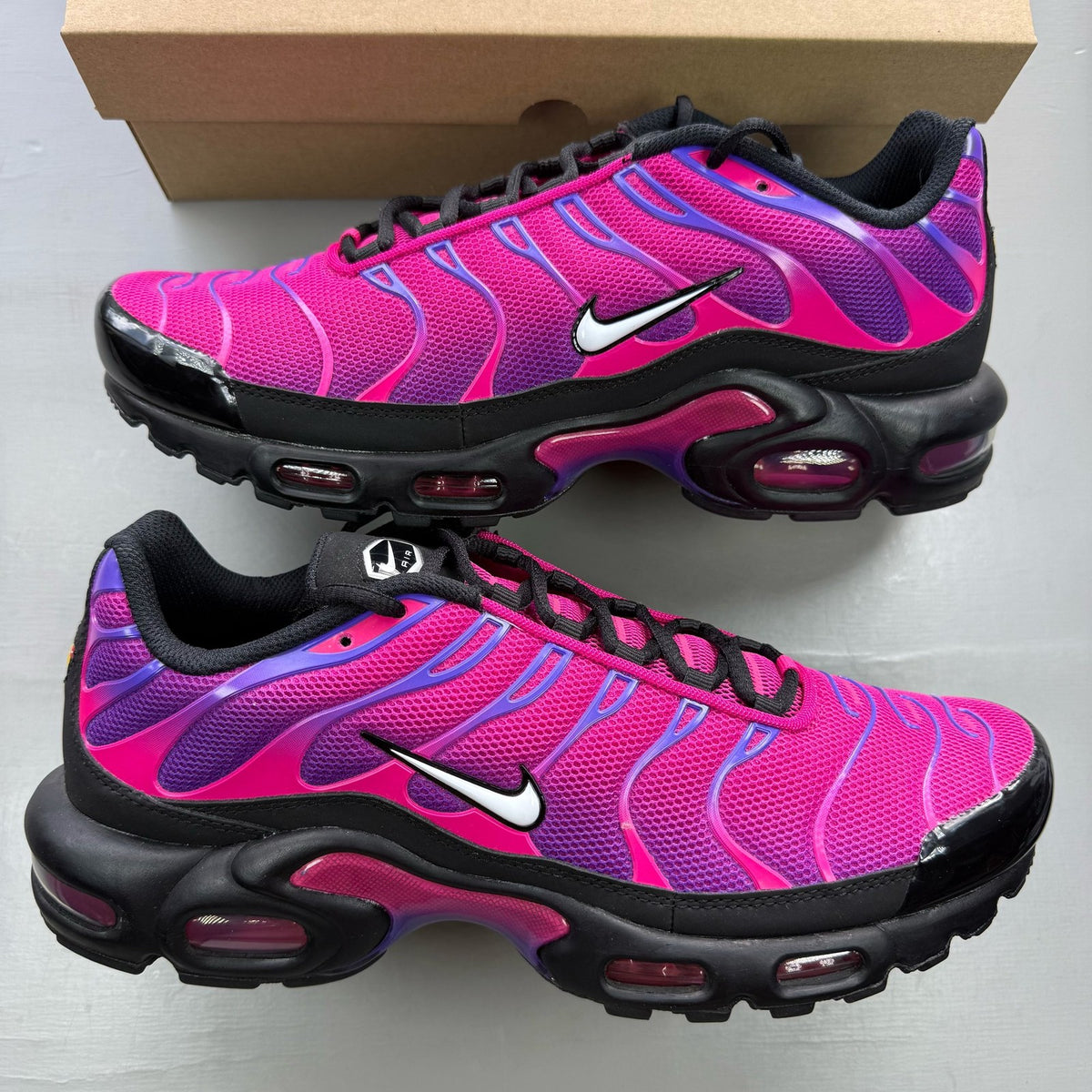 Nike Air Max Plus TN pink and purple trainers with distinctive wave pattern and logo.