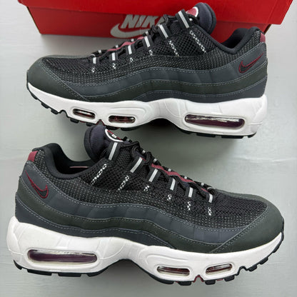 Nike black trainers with red accents and grey detailing, featuring iconic Air Max design.
