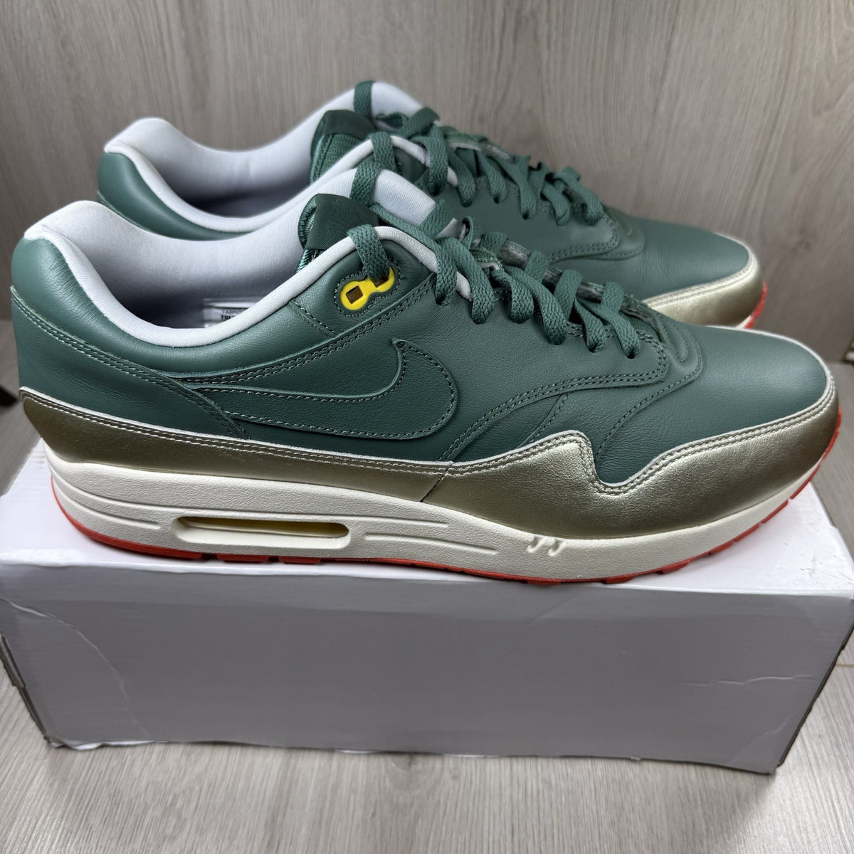 Nike Air Max 1 trainers green with white and silver accents, featuring iconic logo.