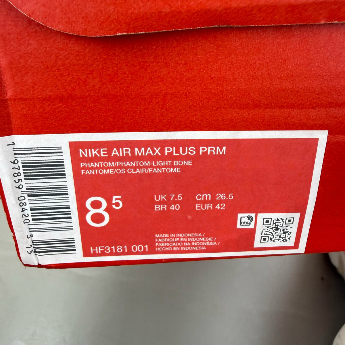 Nike Air Max Plus TN white trainers with burgundy accents and visible logo details.