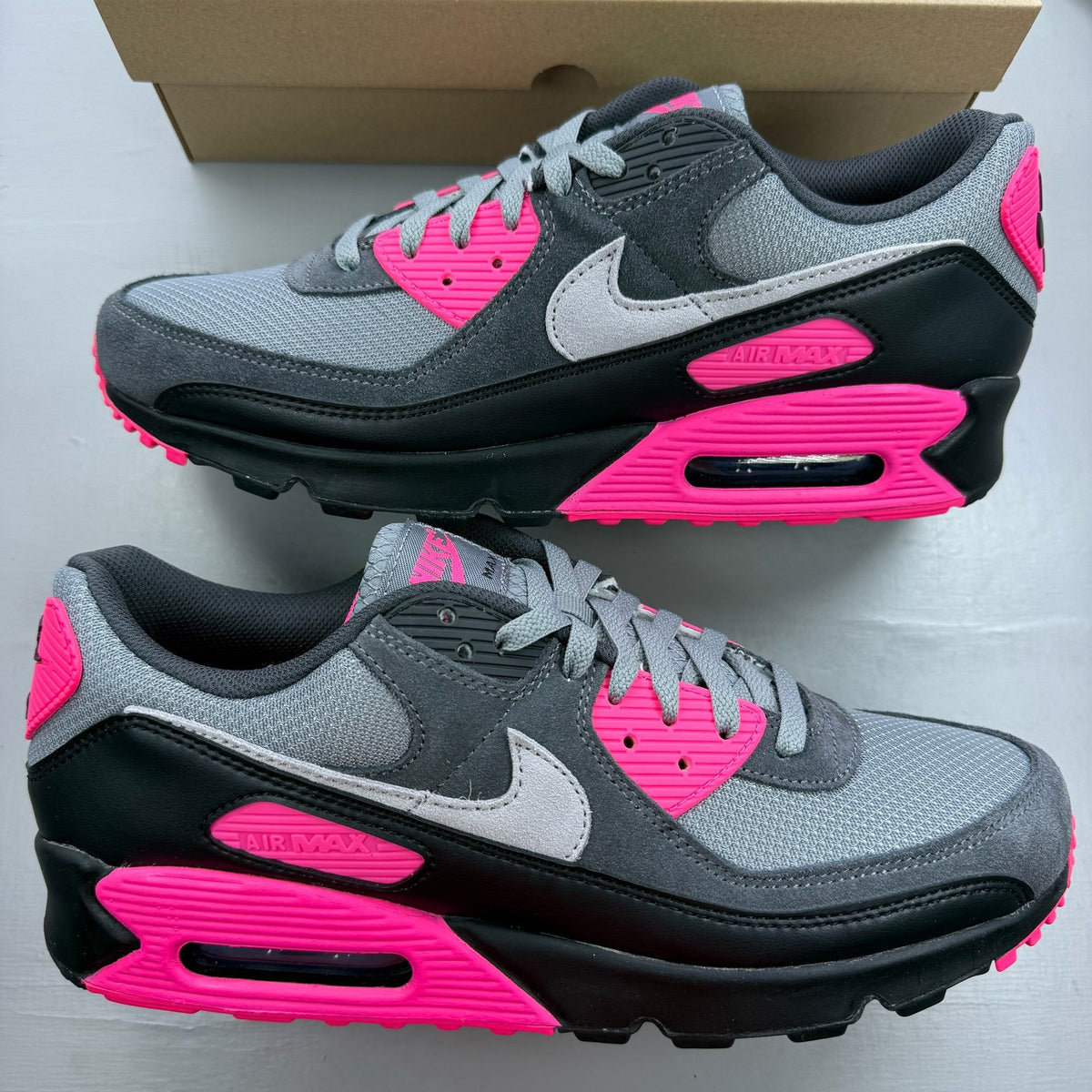 Nike Air Max 90 grey trainers with hyper pink accents and black detailing.