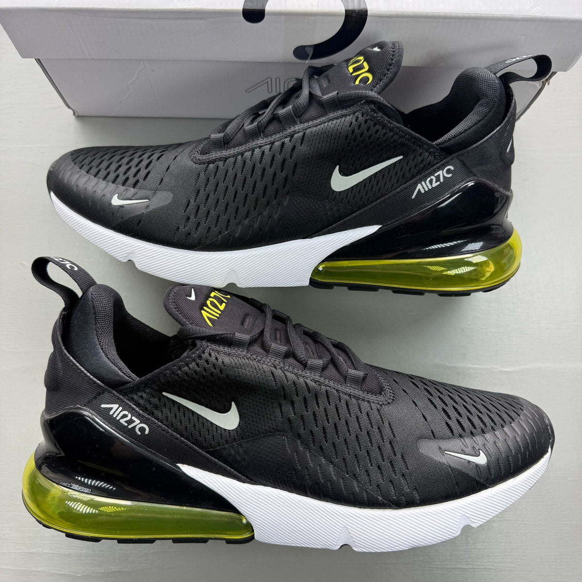 Nike black trainers with Opti Yellow accents and Air Max cushioning.