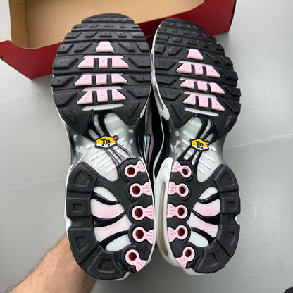Nike Air Max Plus TN black trainers with pink accents and signature swoosh logo.