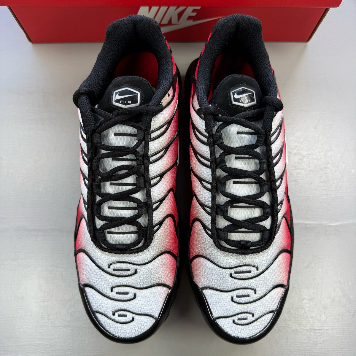 Nike Air Max Plus TN red with pure platinum accents and iconic logo detail.