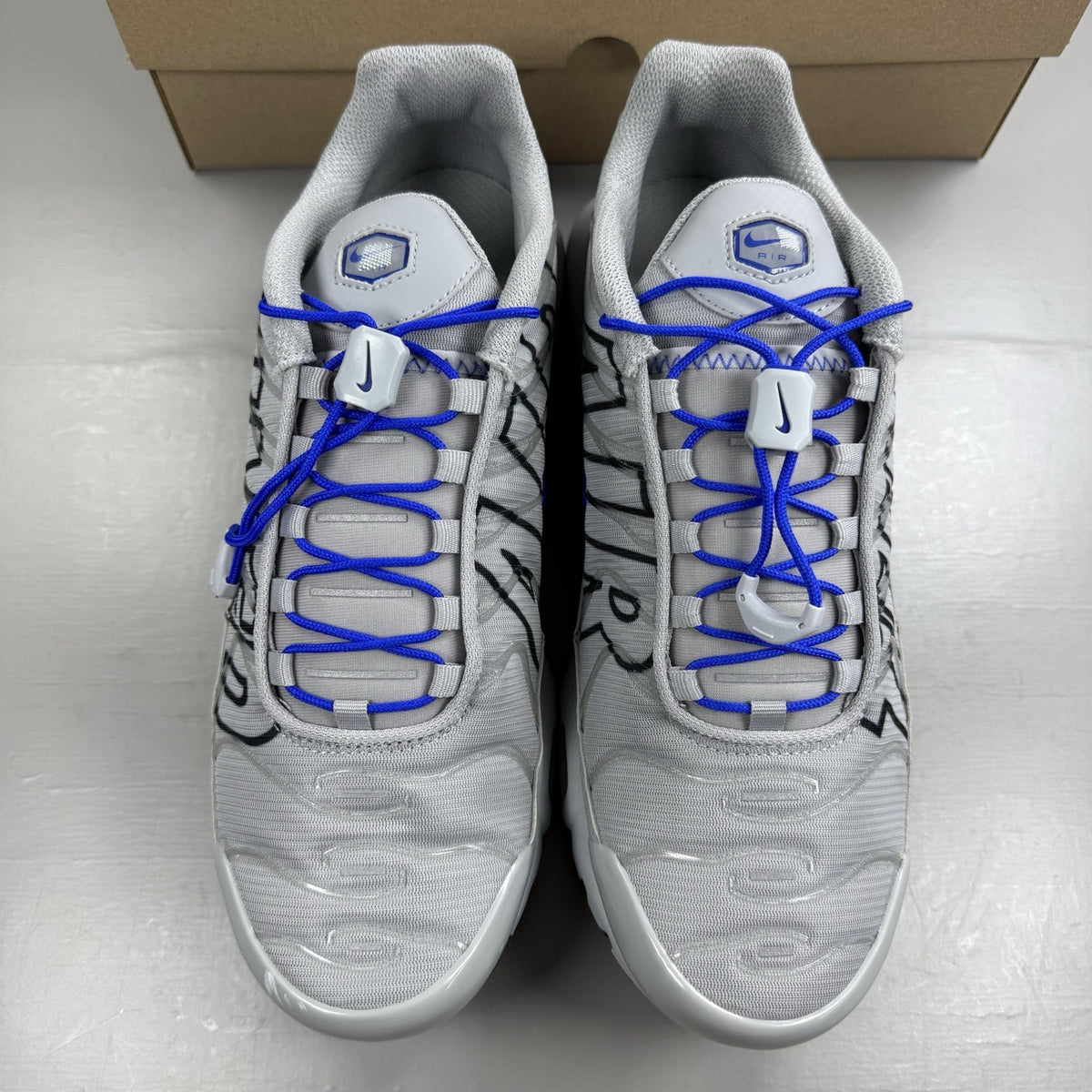 Nike Air Max Plus TN trainers grey with racer blue accents and unique design details.