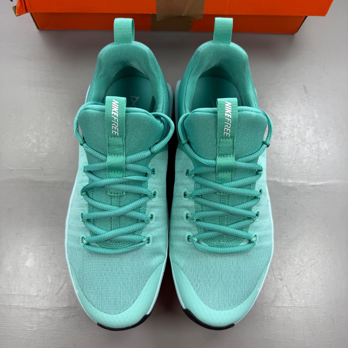 Nike white trainers with bleached turquoise accents and logo detail.