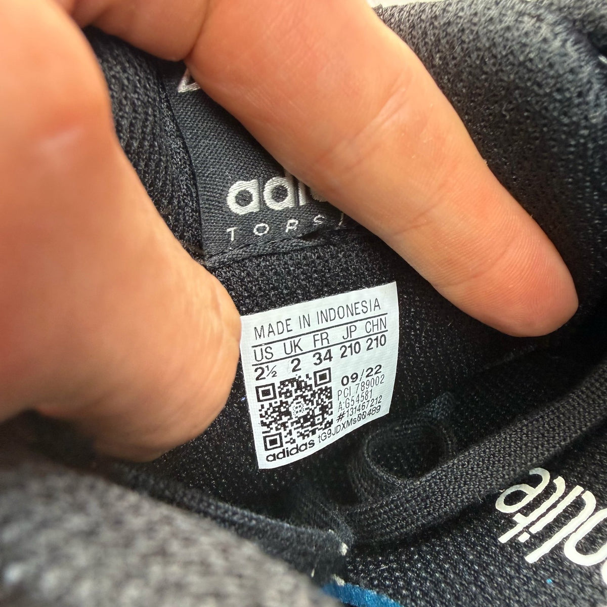 Adidas black trainers with sleek design and logo detail, perfect for kids.