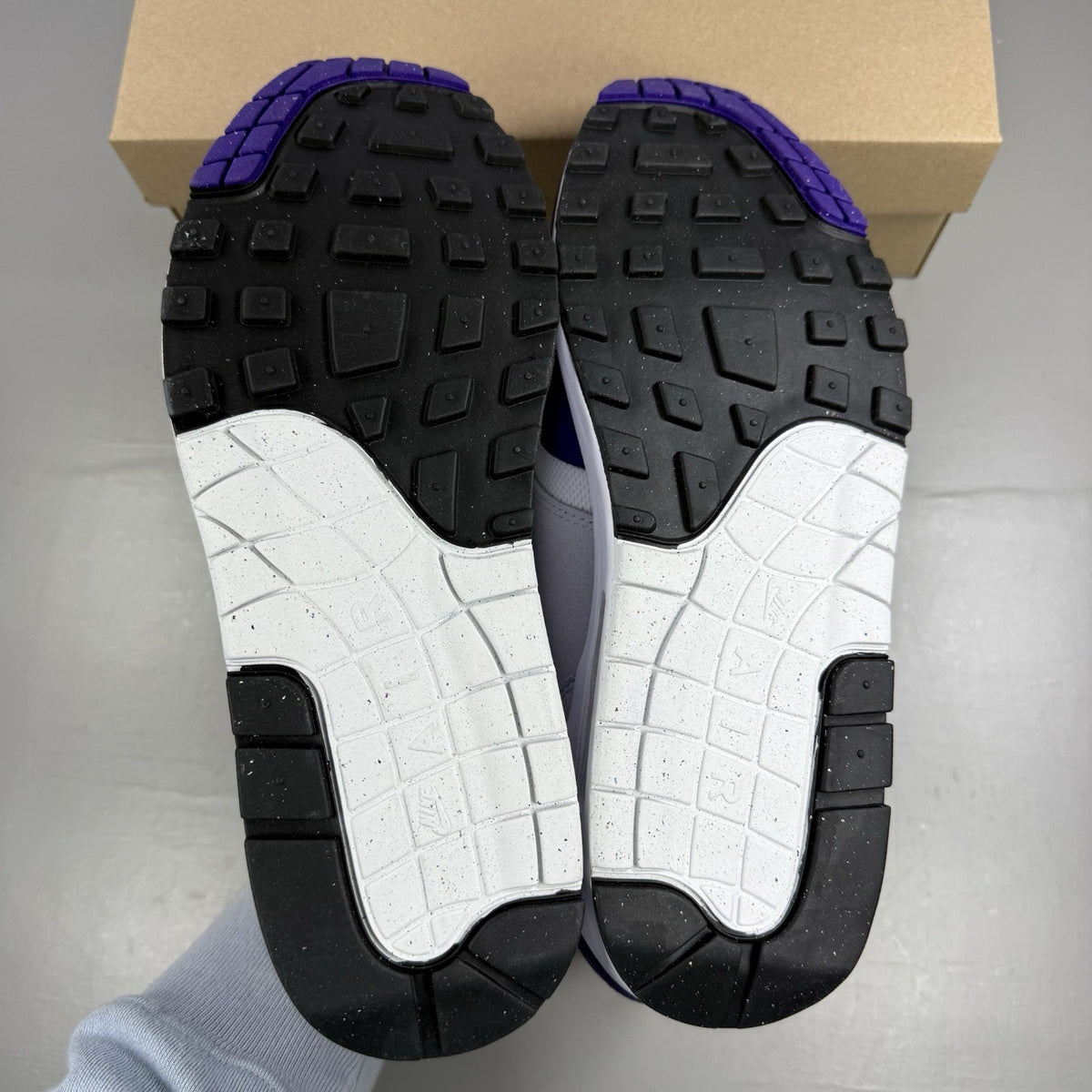Nike Air Max 1 SC white trainers with purple and black accents, featuring logo detail.
