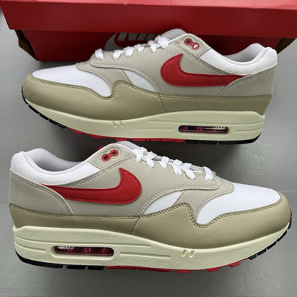 Nike Air Max 1 trainers white with university red accents and cream detailing.