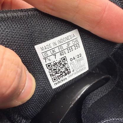 Adidas black deck shoes with three stripes logo and textured upper.