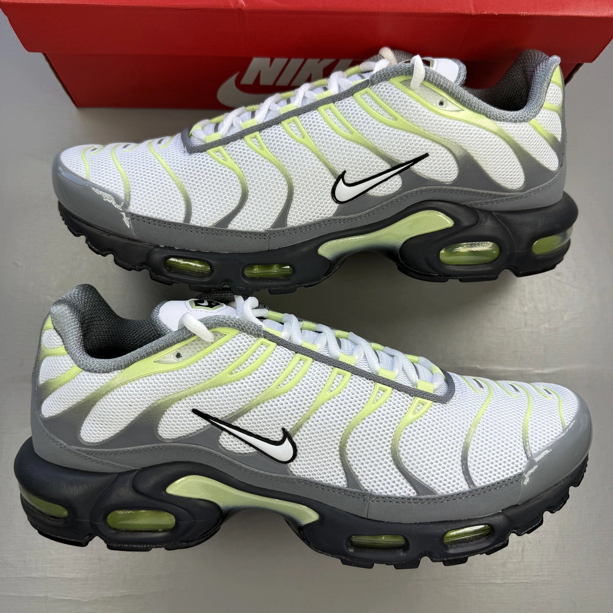 Nike Air Max Plus TN grey trainers with white and liquid lime accents, logo detail.