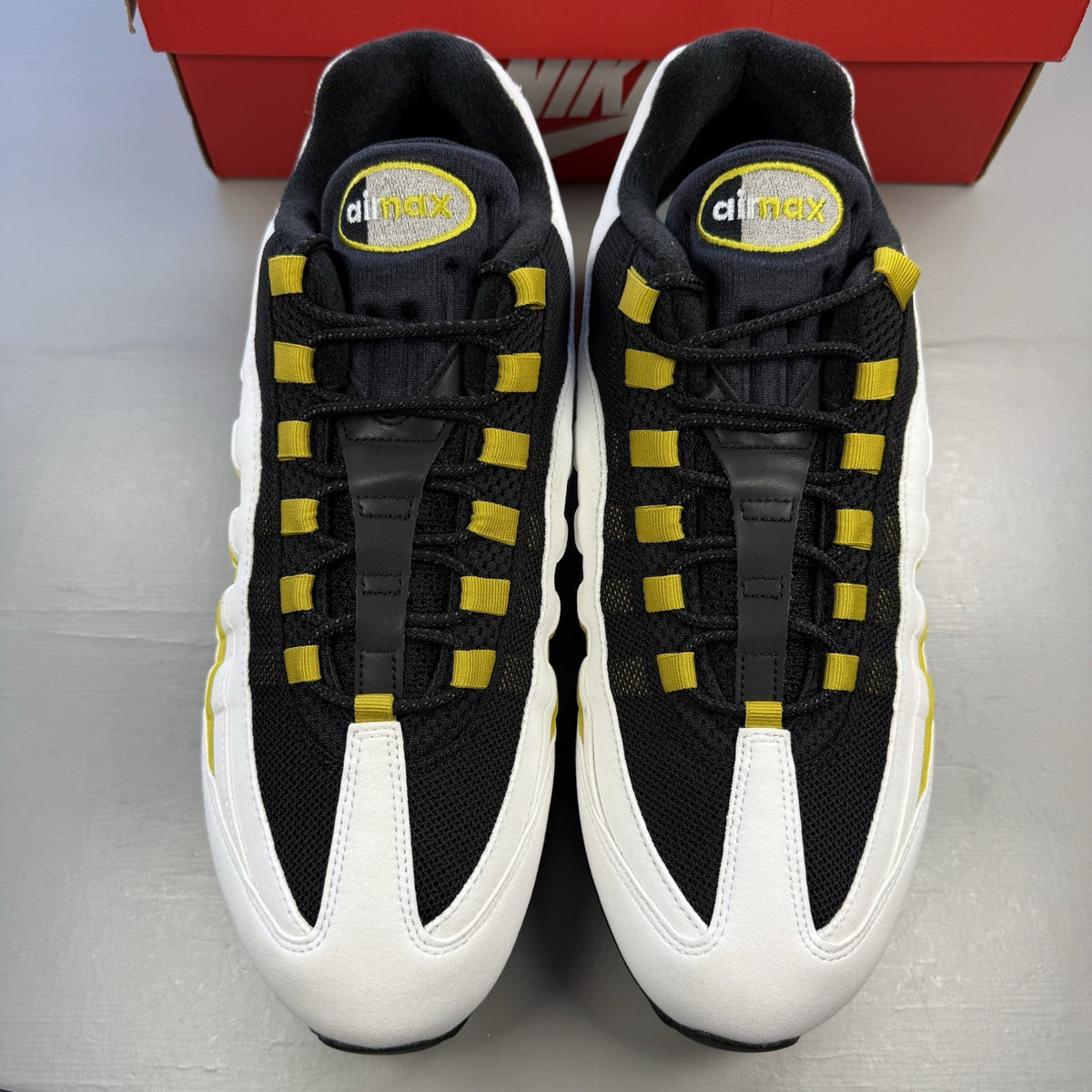 Nike Air Max 95 trainers black with white and saffron accents, featuring iconic logo.
