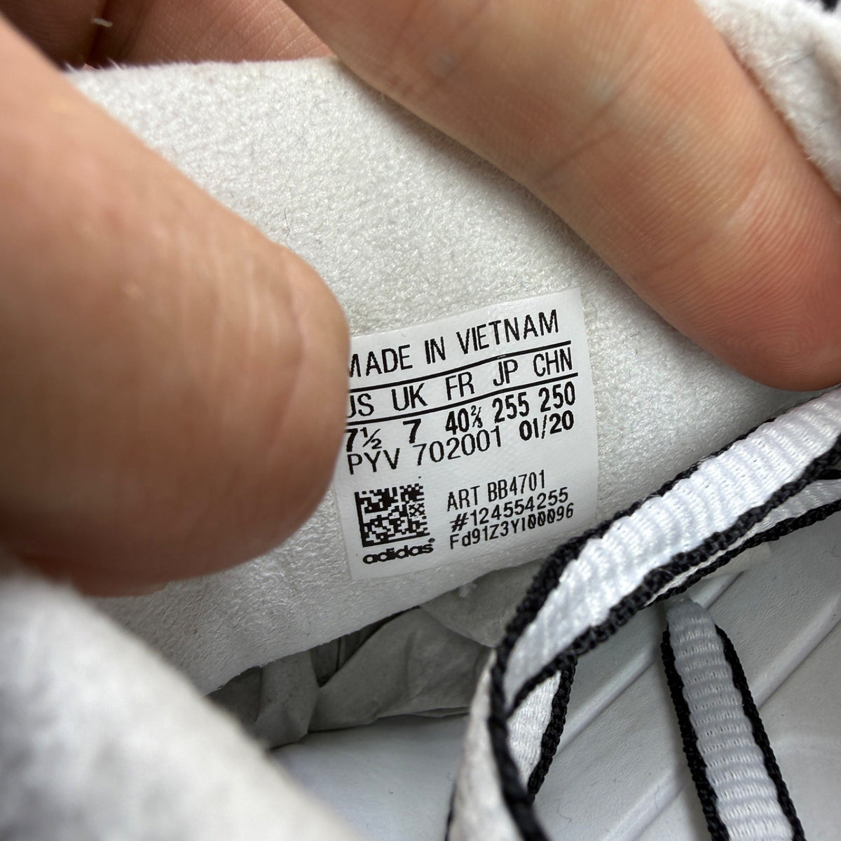 Adidas white trainers with black accents and iconic three stripes design.