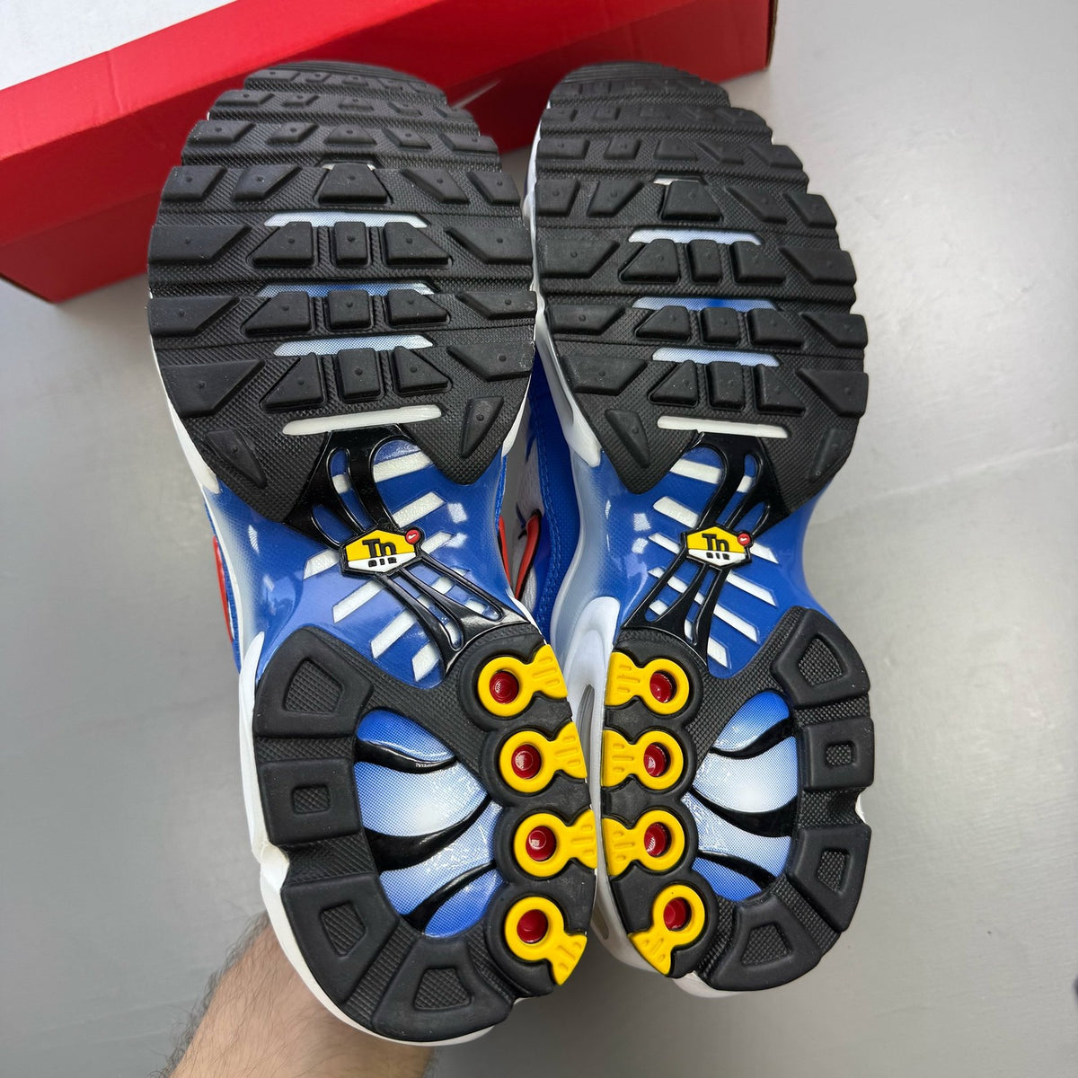 Nike Air Max Plus TN white trainers with blue accents and signature logo details.