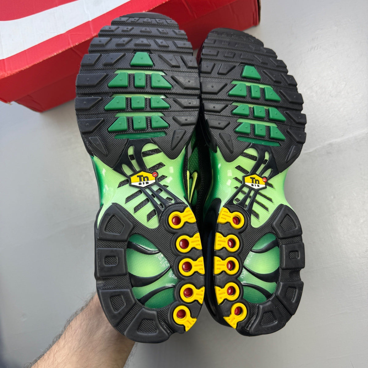 Nike Air Max Plus TN green trainers with logo detailing and mesh material.