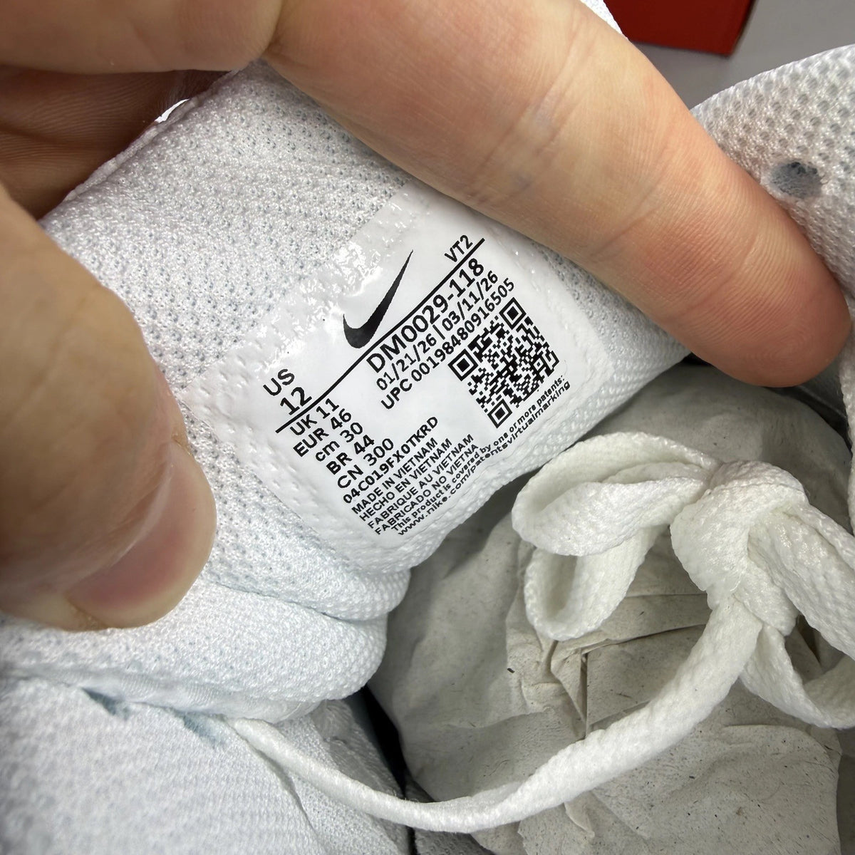 Nike Air Max 90 white trainers with light crimson accents and signature swoosh logo.