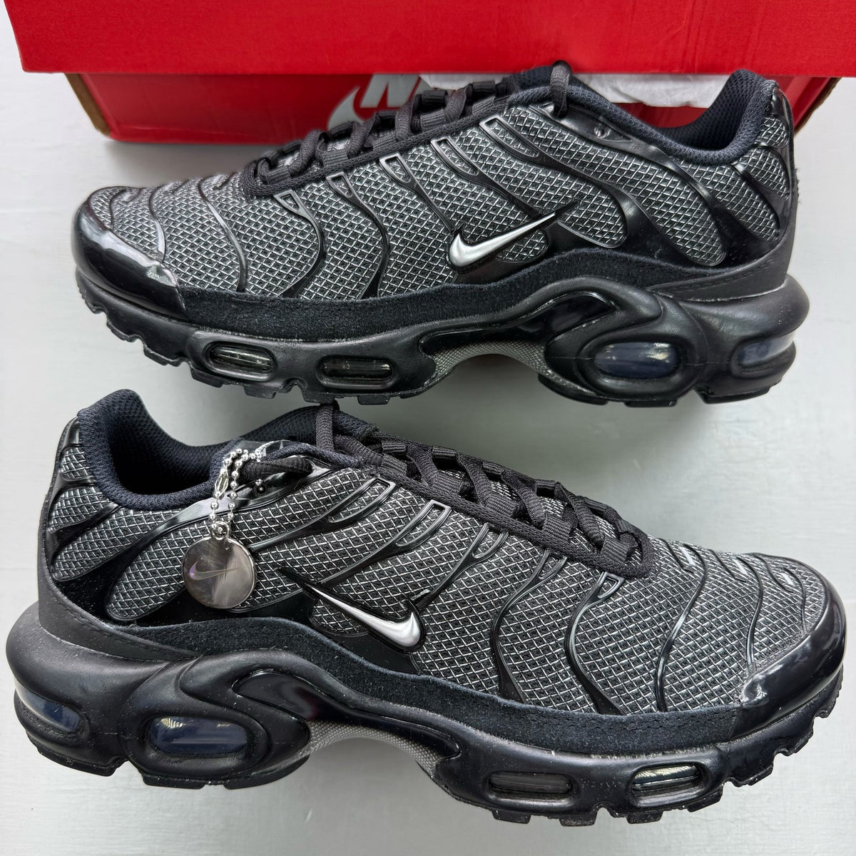 Nike black trainers suede material with silver accents and iconic Air Max Plus design.