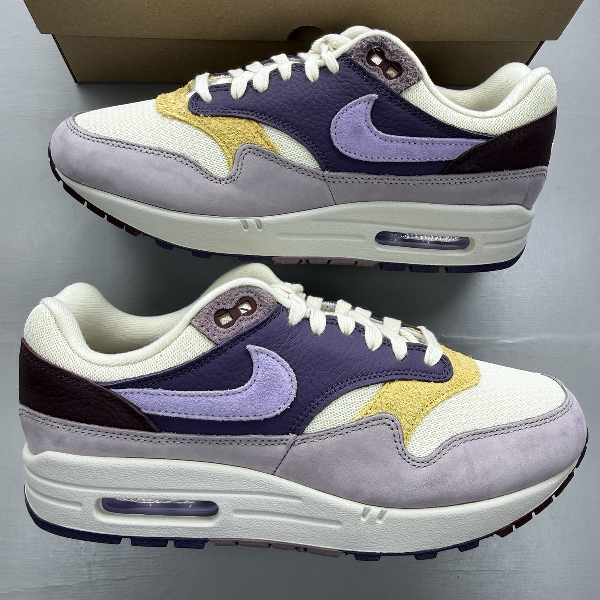 Nike Air Max 1 87 trainers grey with violet accents and signature swoosh logo.