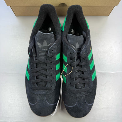 Adidas black Gazelle trainers with green accents and classic logo detailing.