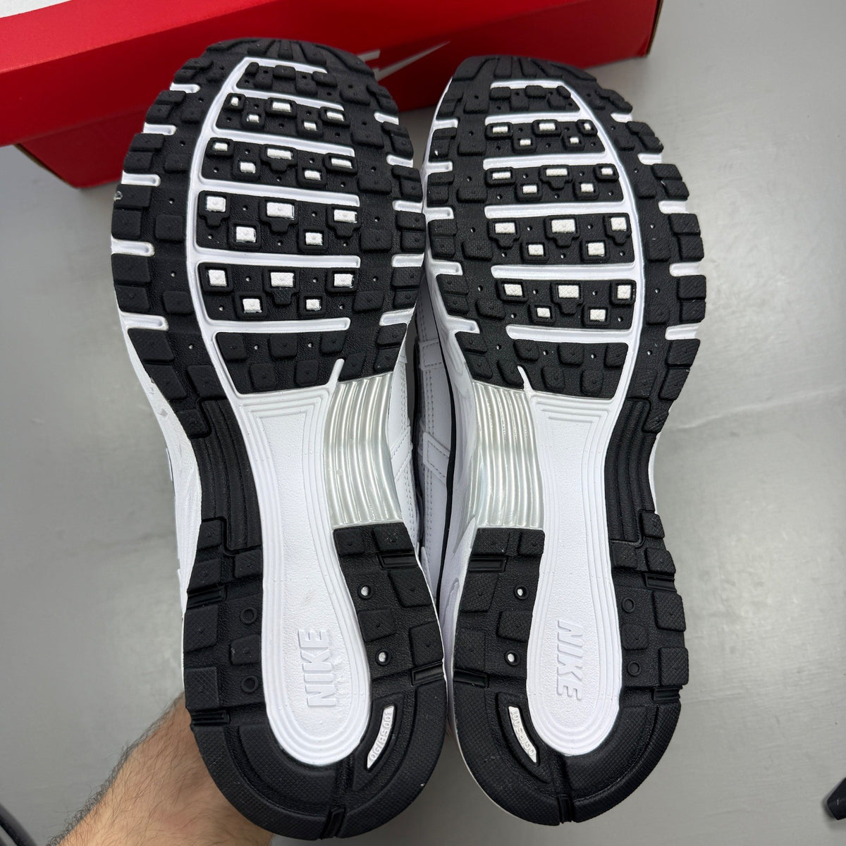 Nike white trainers with metallic silver accents and black detailing, featuring a sleek design.