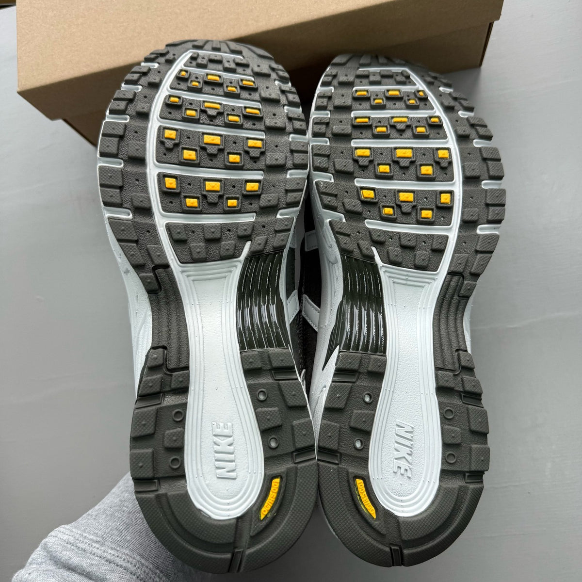 Nike grey P-6000 trainers with laser orange accents and mesh material.
