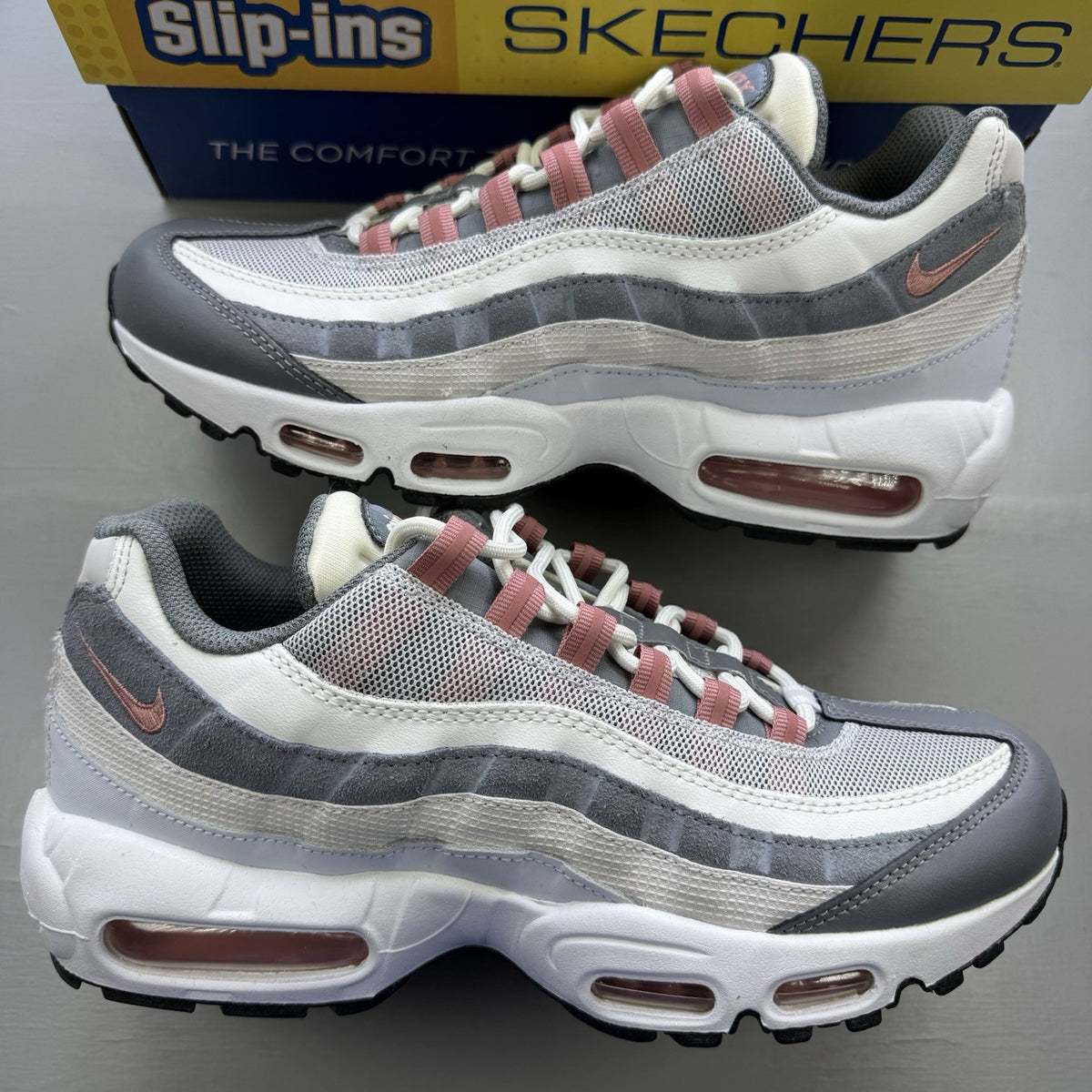 Nike Air Max 95 grey trainers with red accents and white sole, featuring iconic logo.