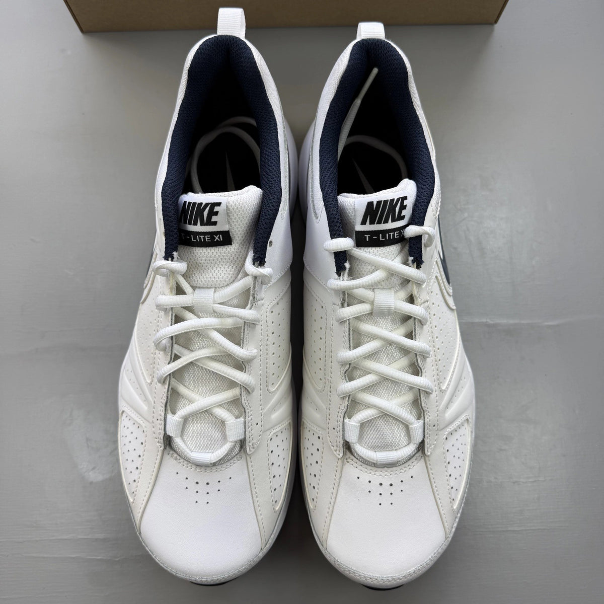 Nike white trainers with navy and black accents, featuring logo detailing and mesh material.