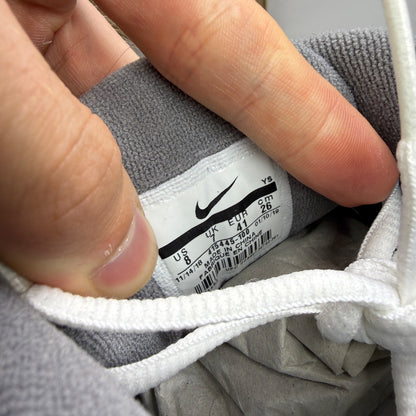 Nike Air Monarch IV white trainers with cool grey and green accents, featuring logo detail.