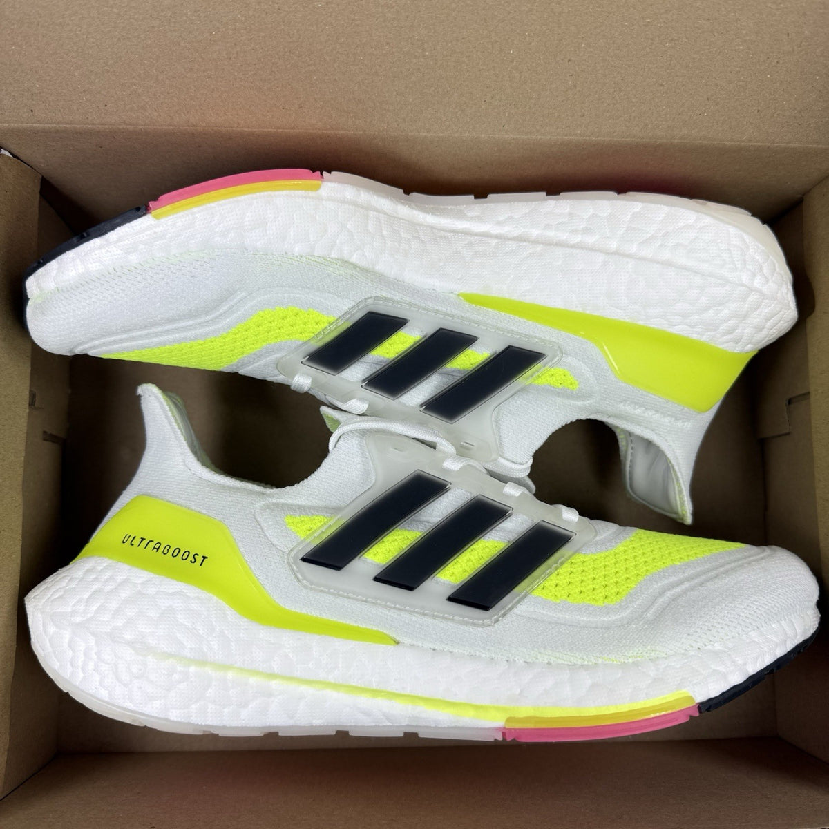 Adidas Ultra Boost 21 white trainers with solar yellow accents and signature three-stripe logo.