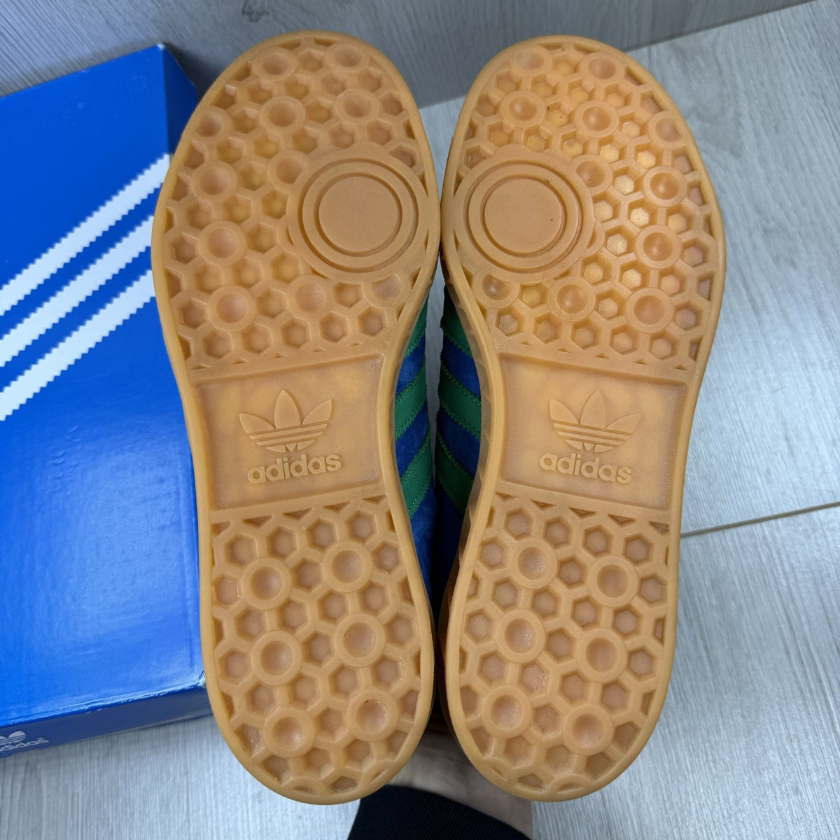 Adidas blue trainers with gum sole and iconic three-stripe logo design.