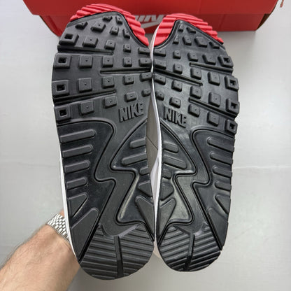 Nike Air Max 90 white trainers with black and red accents, featuring iconic logo and design.