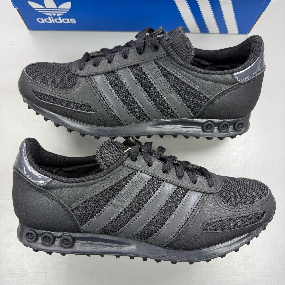 Adidas black deck shoes with three stripes logo and textured upper.
