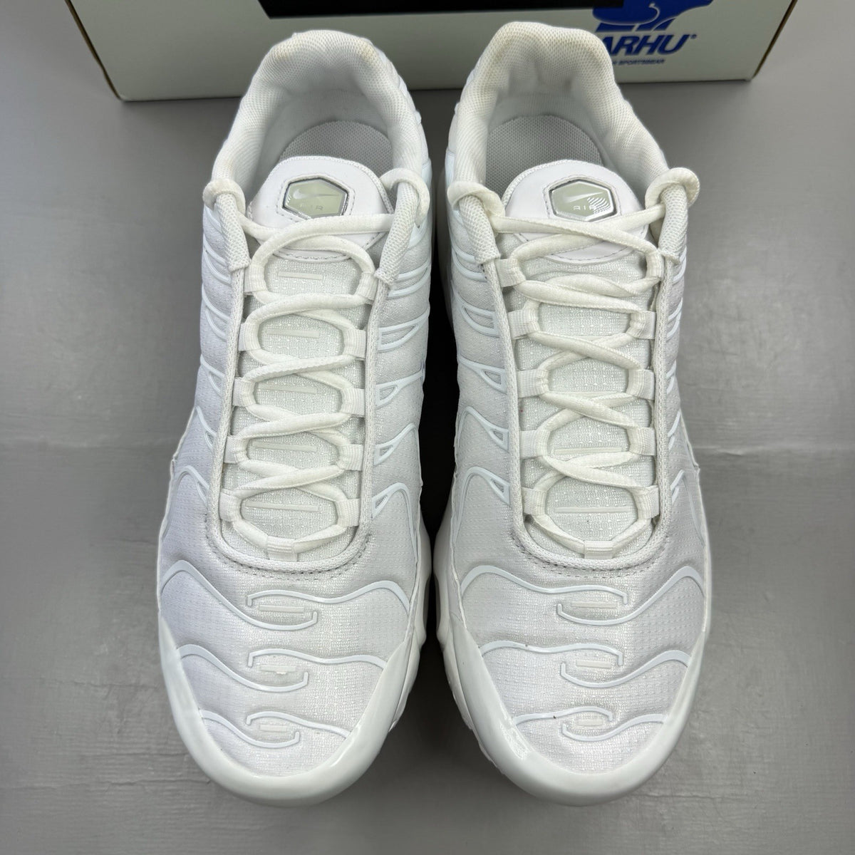 Nike Air Max Plus TN white trainers with metallic silver accents and grey detailing.