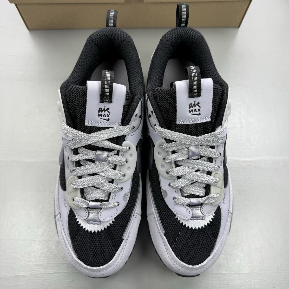 Nike Air Max 90 Futura black trainers with grey and white accents, sleek design.