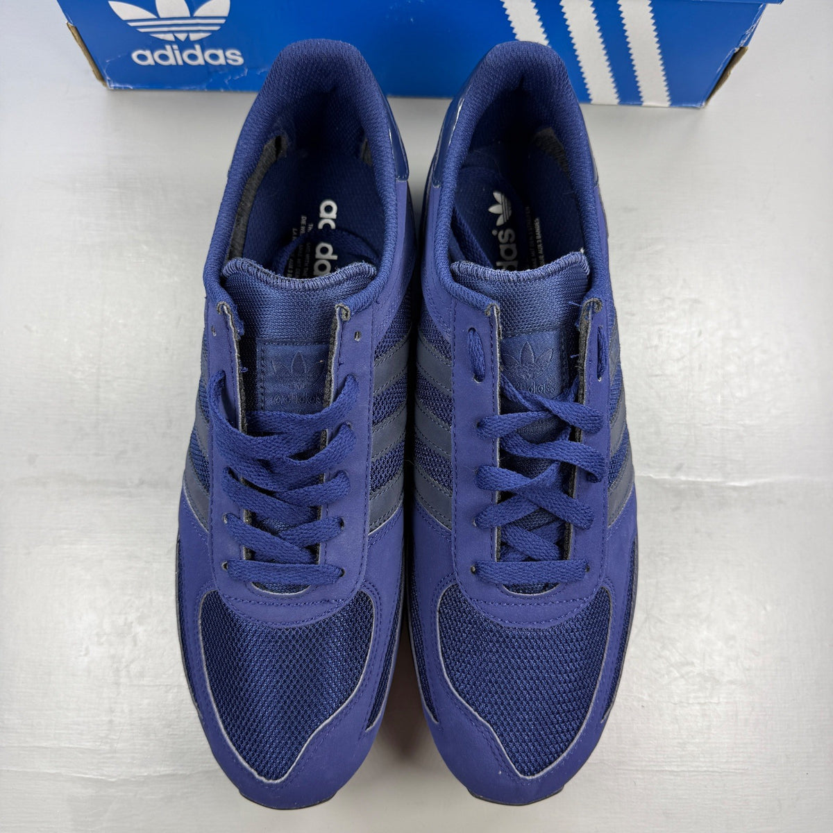 Adidas blue trainers with black accents and signature three-stripe logo.