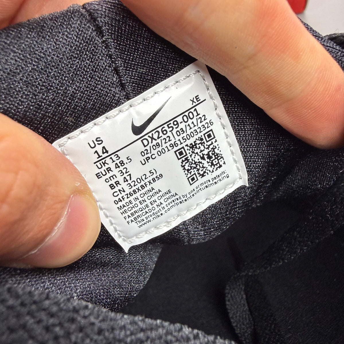Nike black Air Huarache trainers with safety orange accents and white sole.