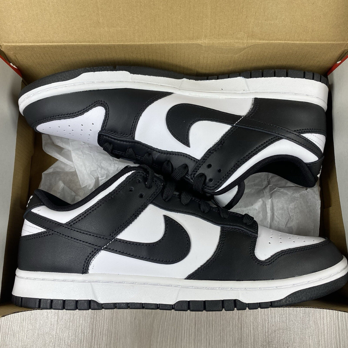 Nike Dunk Low trainers black and white with iconic swoosh logo and smooth leather upper.