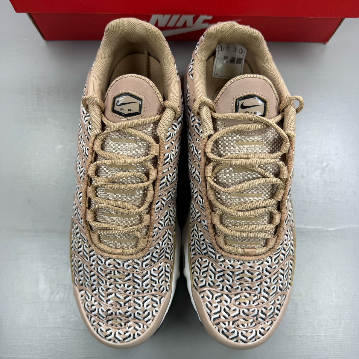Nike Air Max Plus TN beige trainers with iconic logo and sleek design.
