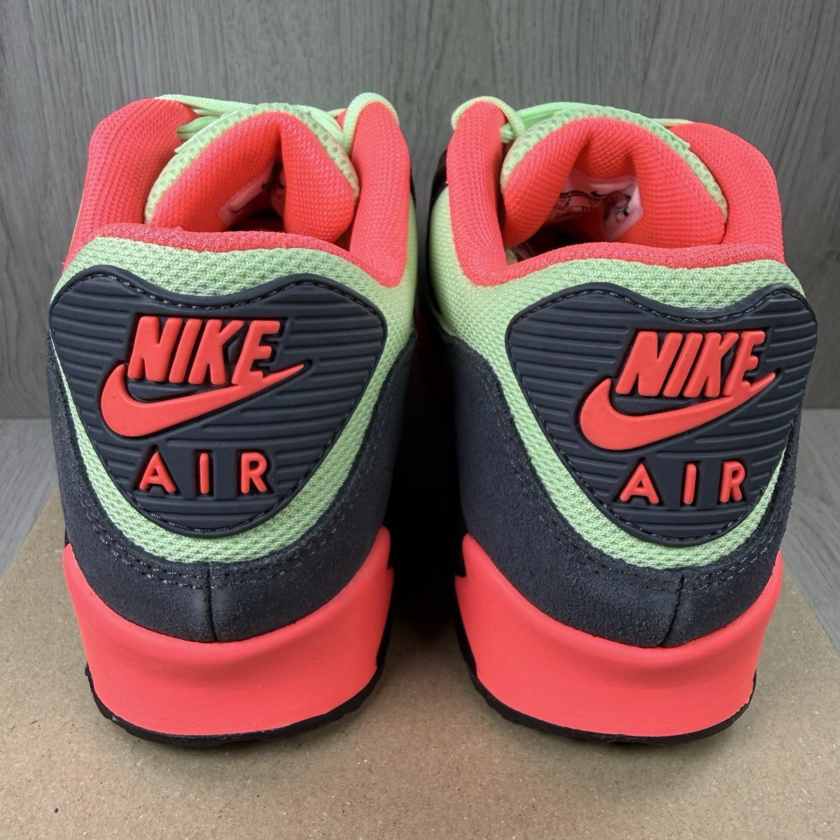 Nike Air Max 90 Essential green trainers with signature swoosh logo and mesh detailing.