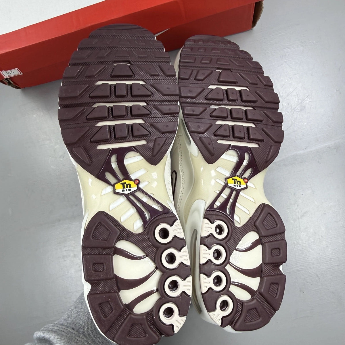 Nike Air Max Plus trainers white with burgundy accents and signature logo details.