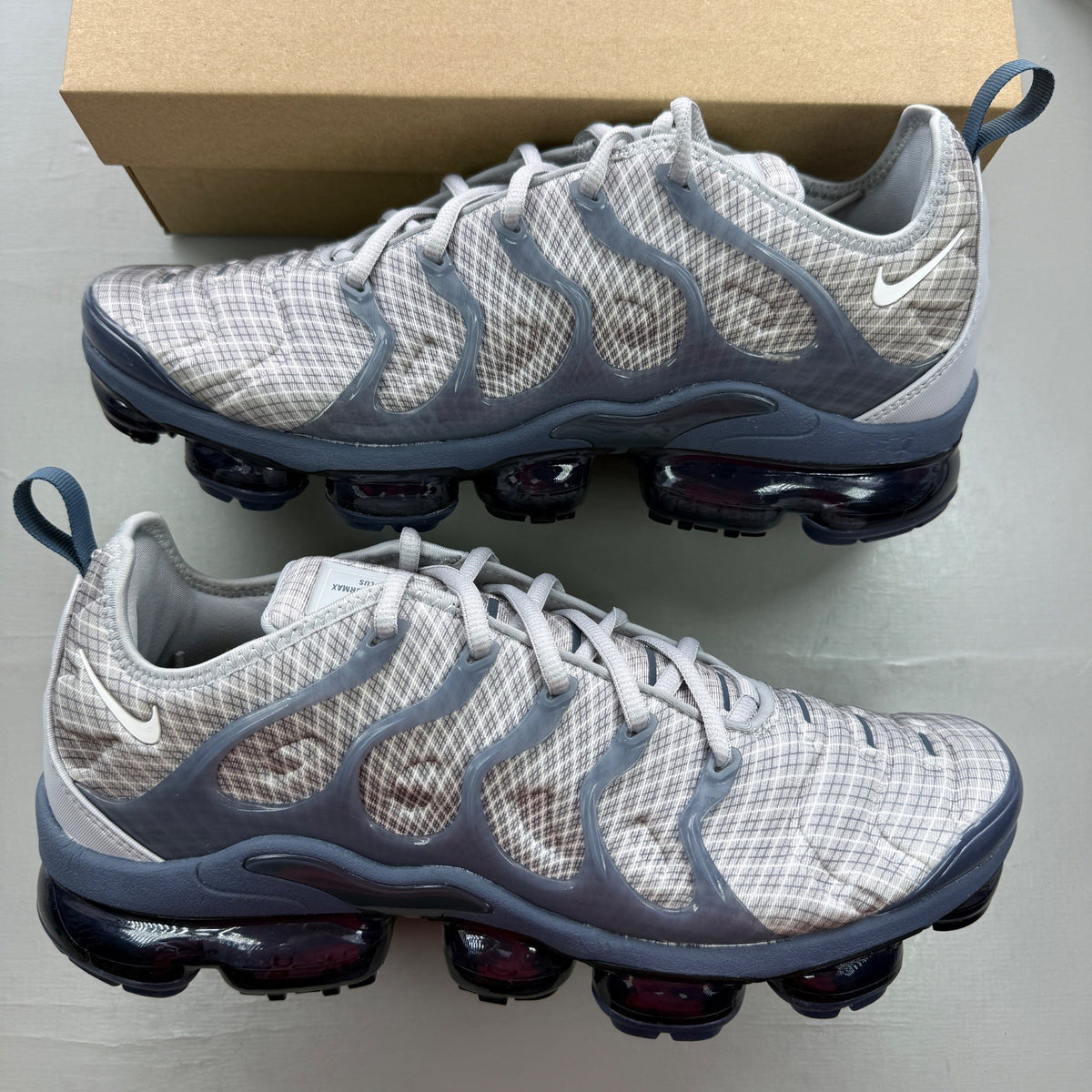 Nike Air VaporMax Plus grey trainers with white accents and signature logo.