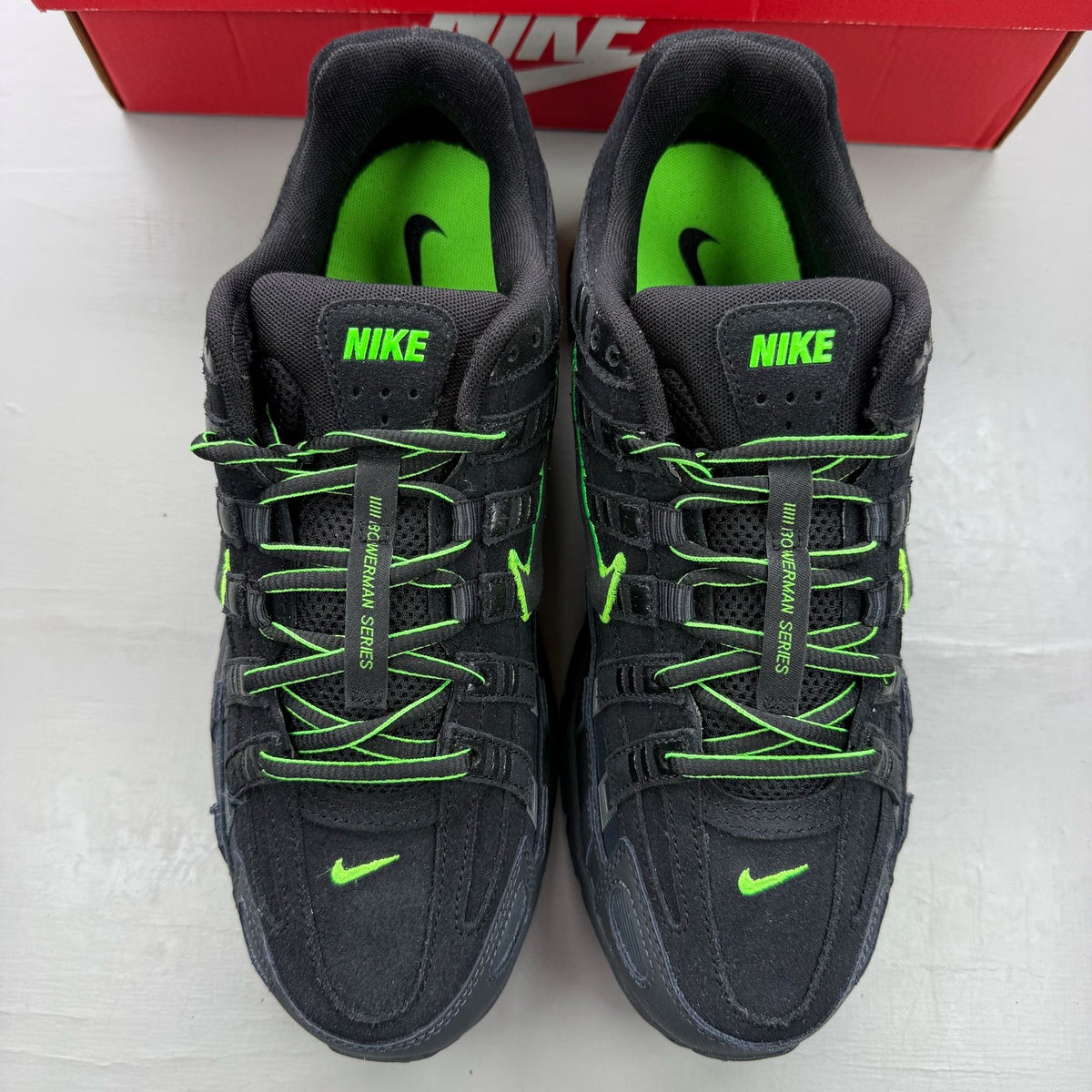 Nike P-6000 black trainers with green accents and mesh panels, 100% authentic.