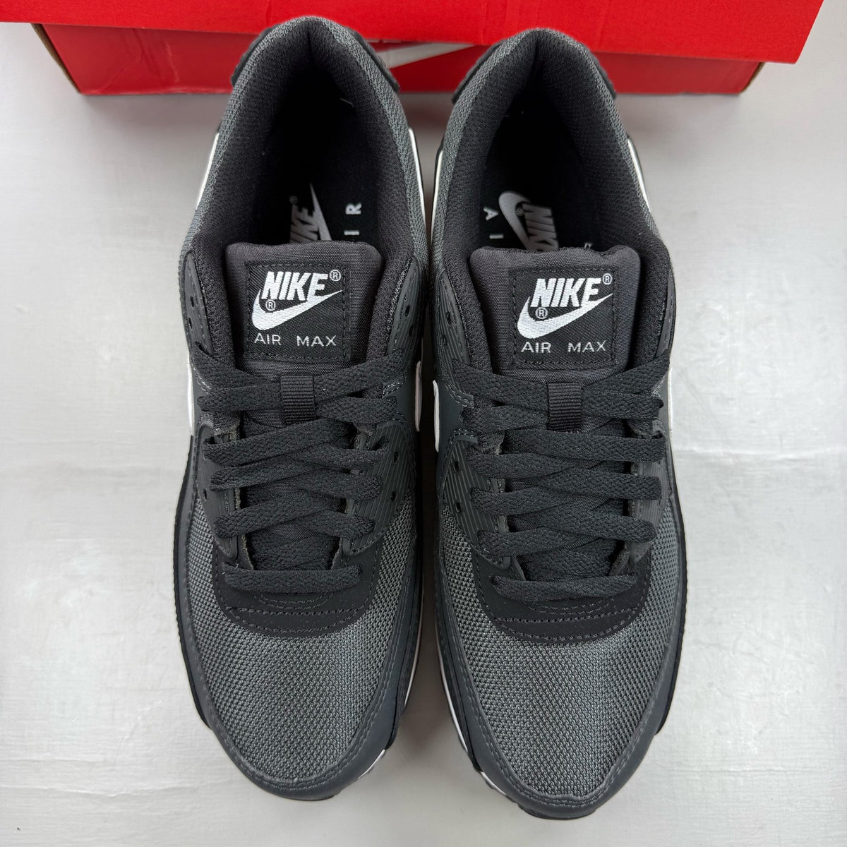 Nike Air Max 90 black trainers with grey accents and signature swoosh logo.
