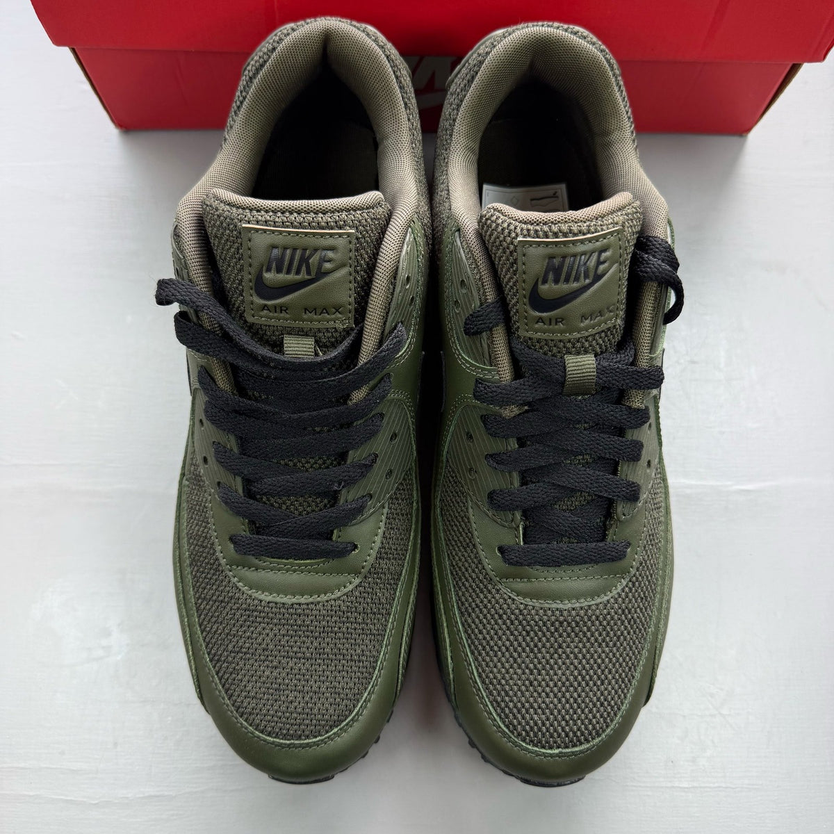 Nike Air Max 90 green trainers with black accents and logo detail.