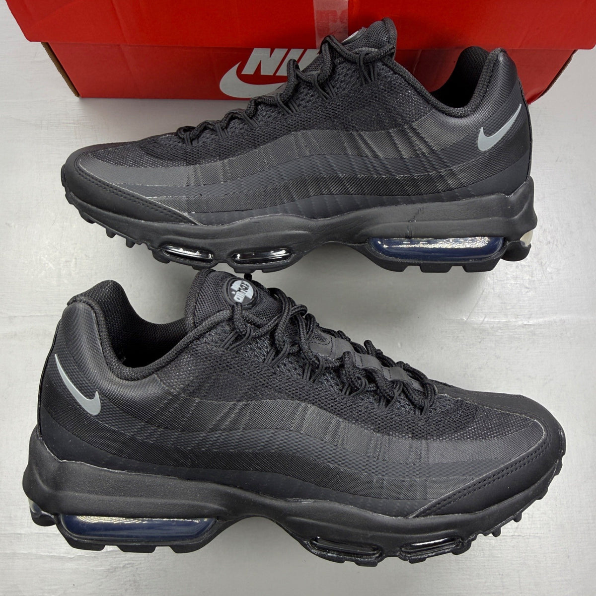 Nike Air Max 95 black trainers with grey accents and textured material.