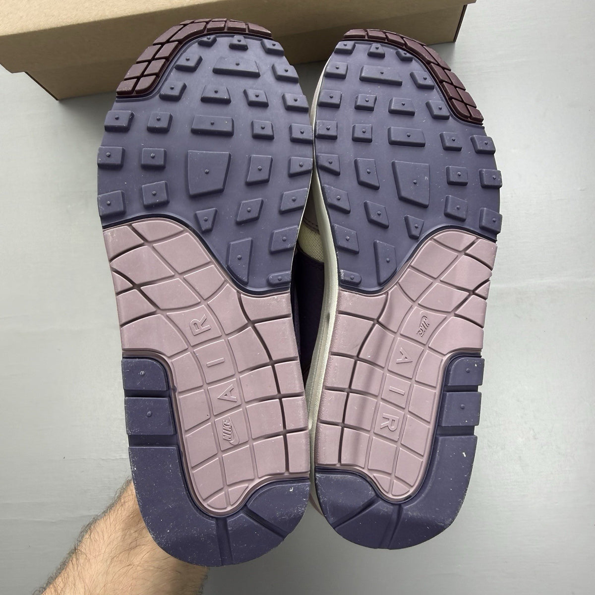 Nike Air Max 1 87 trainers grey with violet accents and signature swoosh logo.