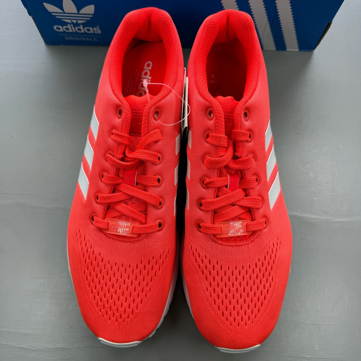 Adidas ZX Flux EM red trainers with white accents and textured mesh upper.