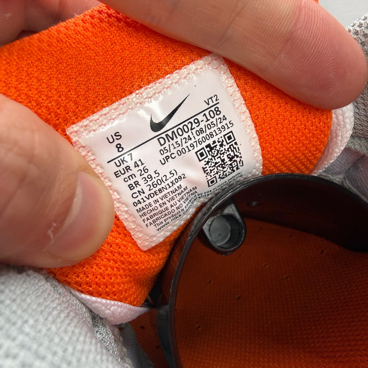 Nike Air Max 90 white trainers with safety orange accents and grey detailing.